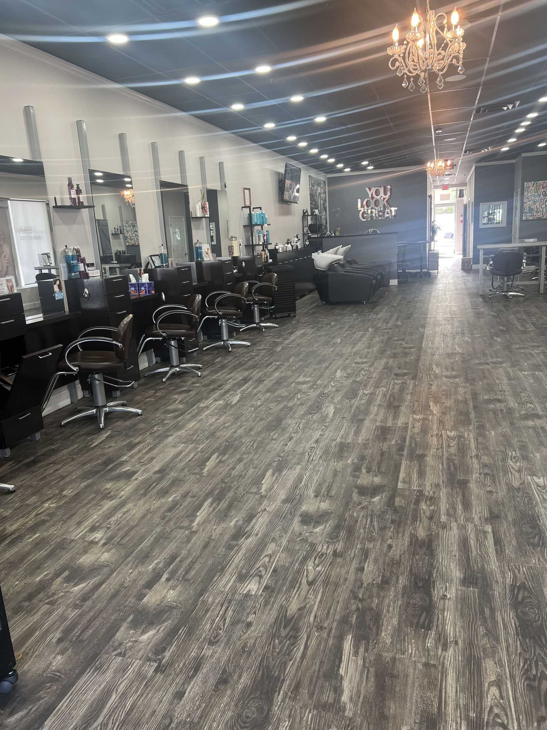 Spacious modern salon with styling stations, mirrors, and chandelier.